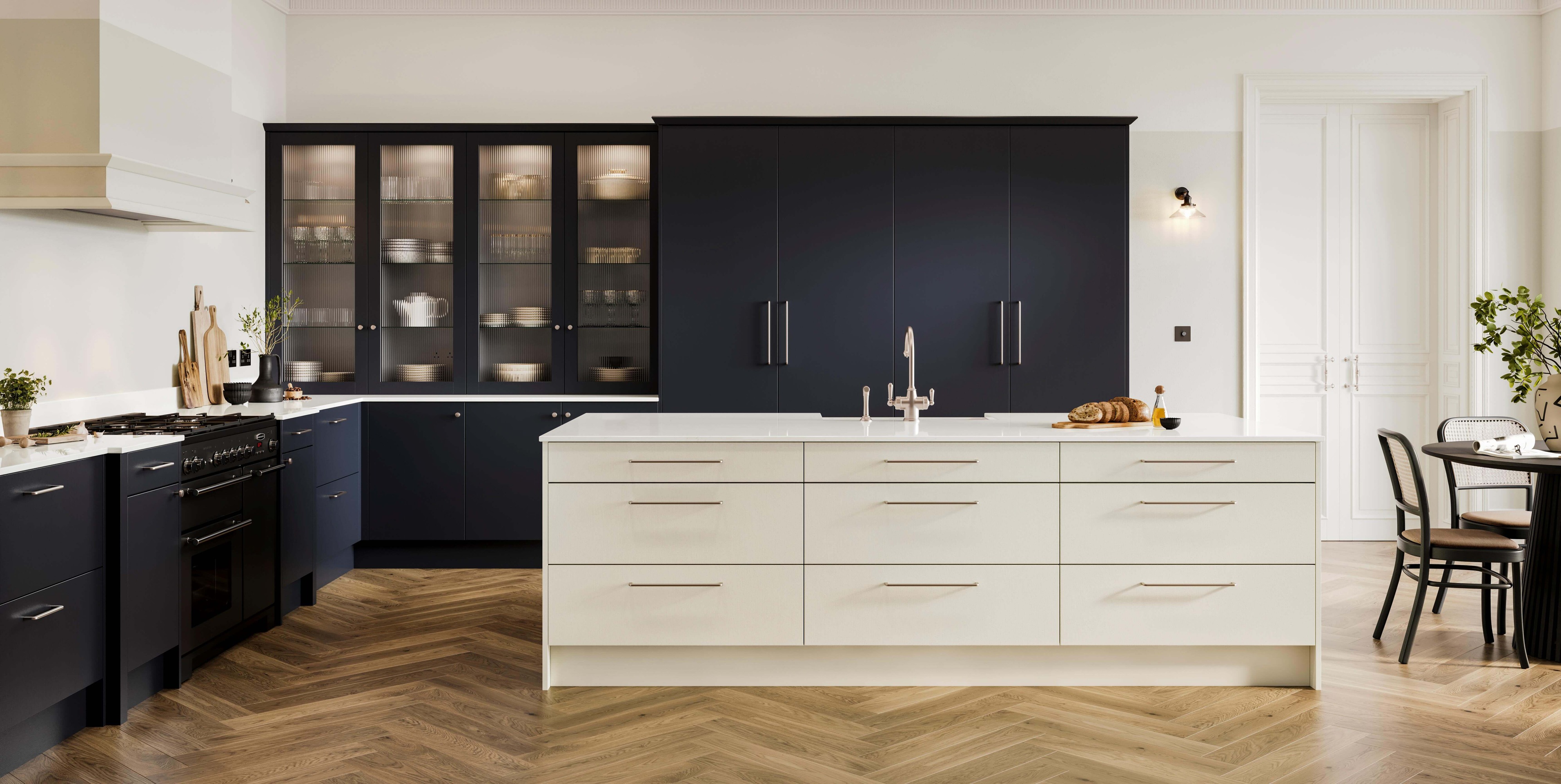 a modern kitchen with a slab door kitchen island painted in a pale grey with dark blue kitchen cabinets at the back