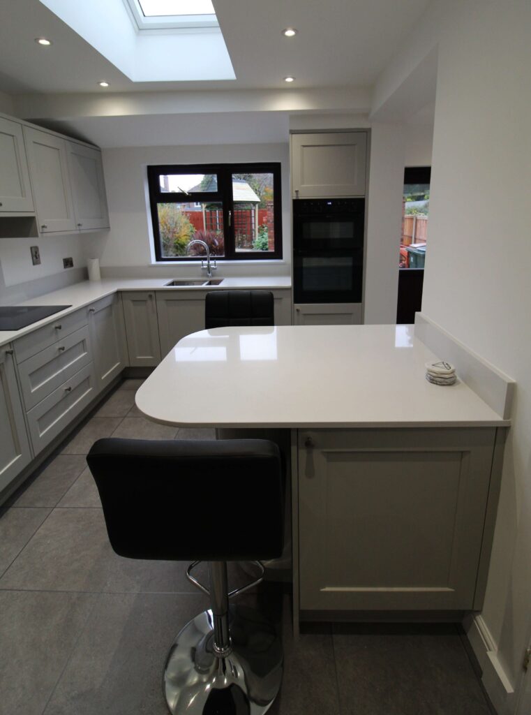 Soft grey shaker kitchen peninsula and black bar stool