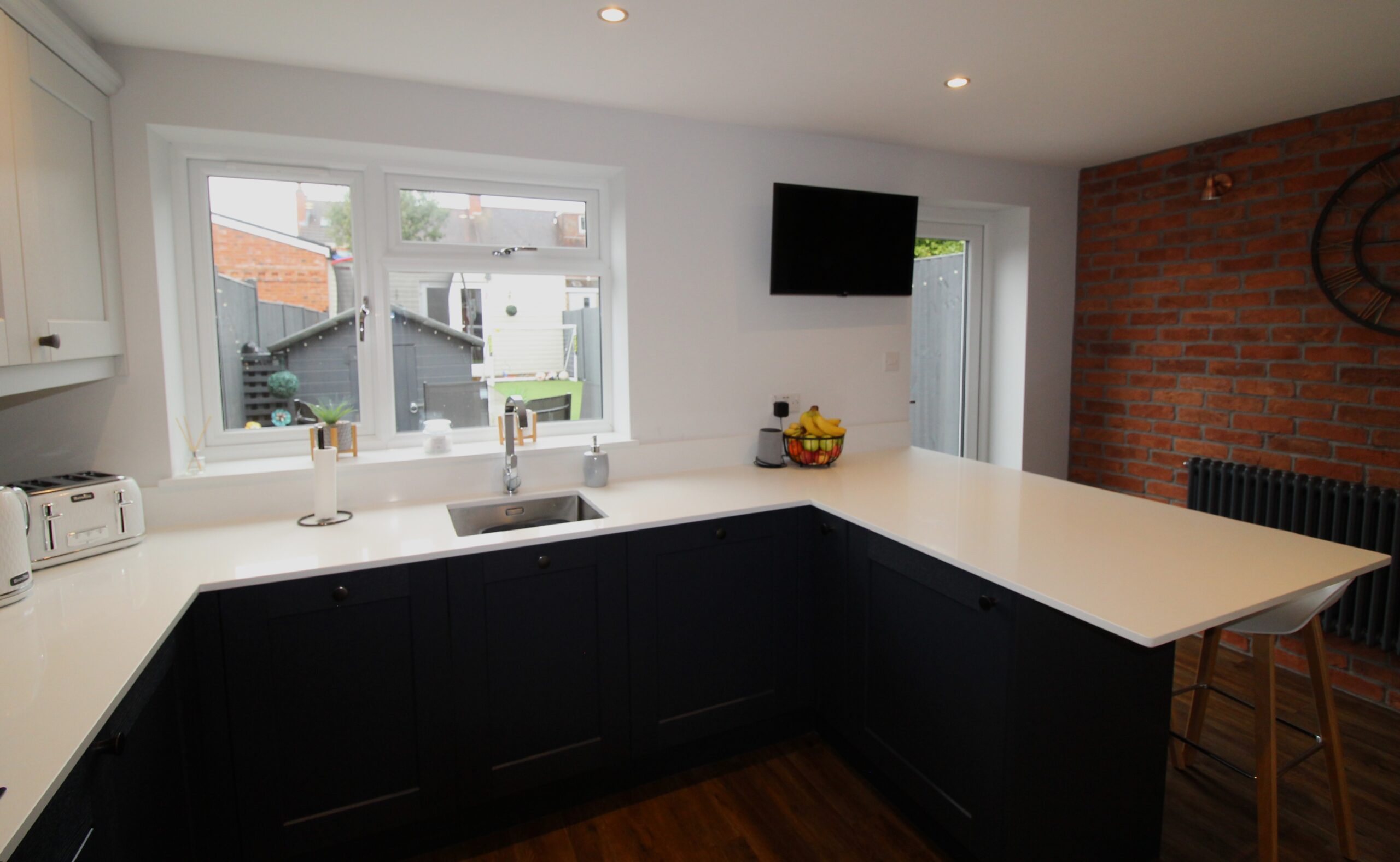 blue and light grey shaker kitchen peninsula with stainless steel sink and chrome tap