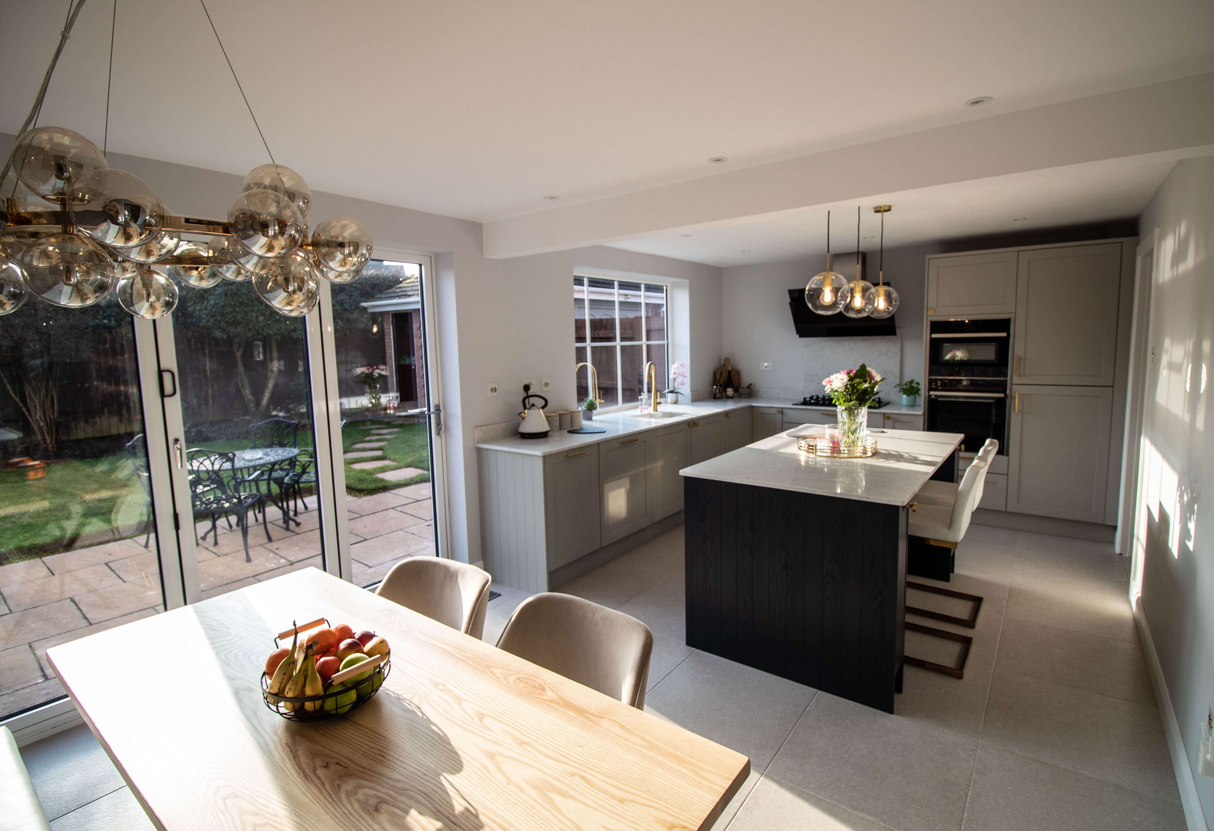grey kitchen cabinets with dark blue central island and white quartz worktop and dining table
