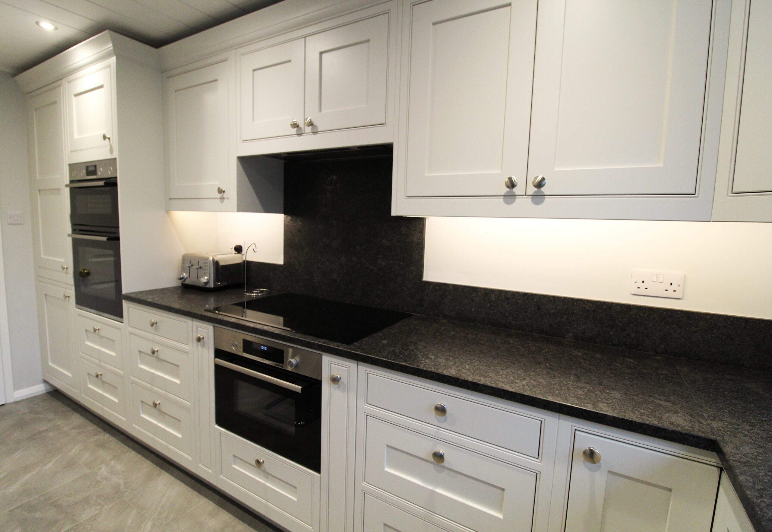 White painted inframe kitchen with black granite worktop, Bosch oven, induction hob and canopy extractor