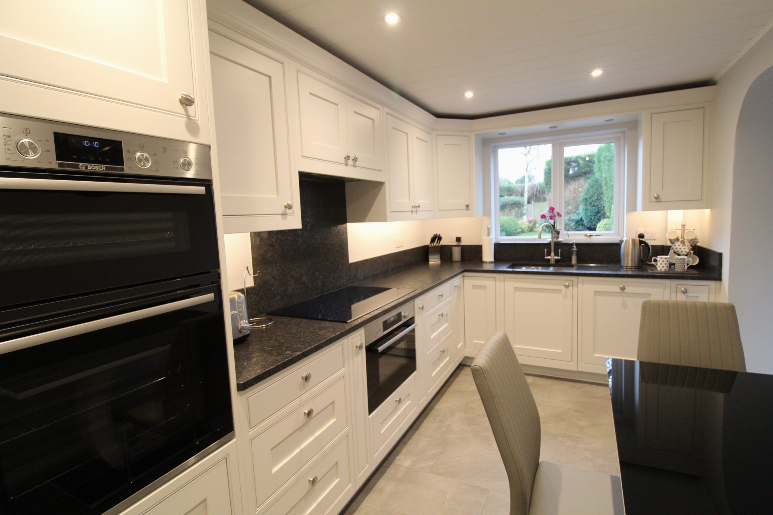 White painted inframe kitchen with black granite worktop, Bosch oven, induction hob and canopy extractor