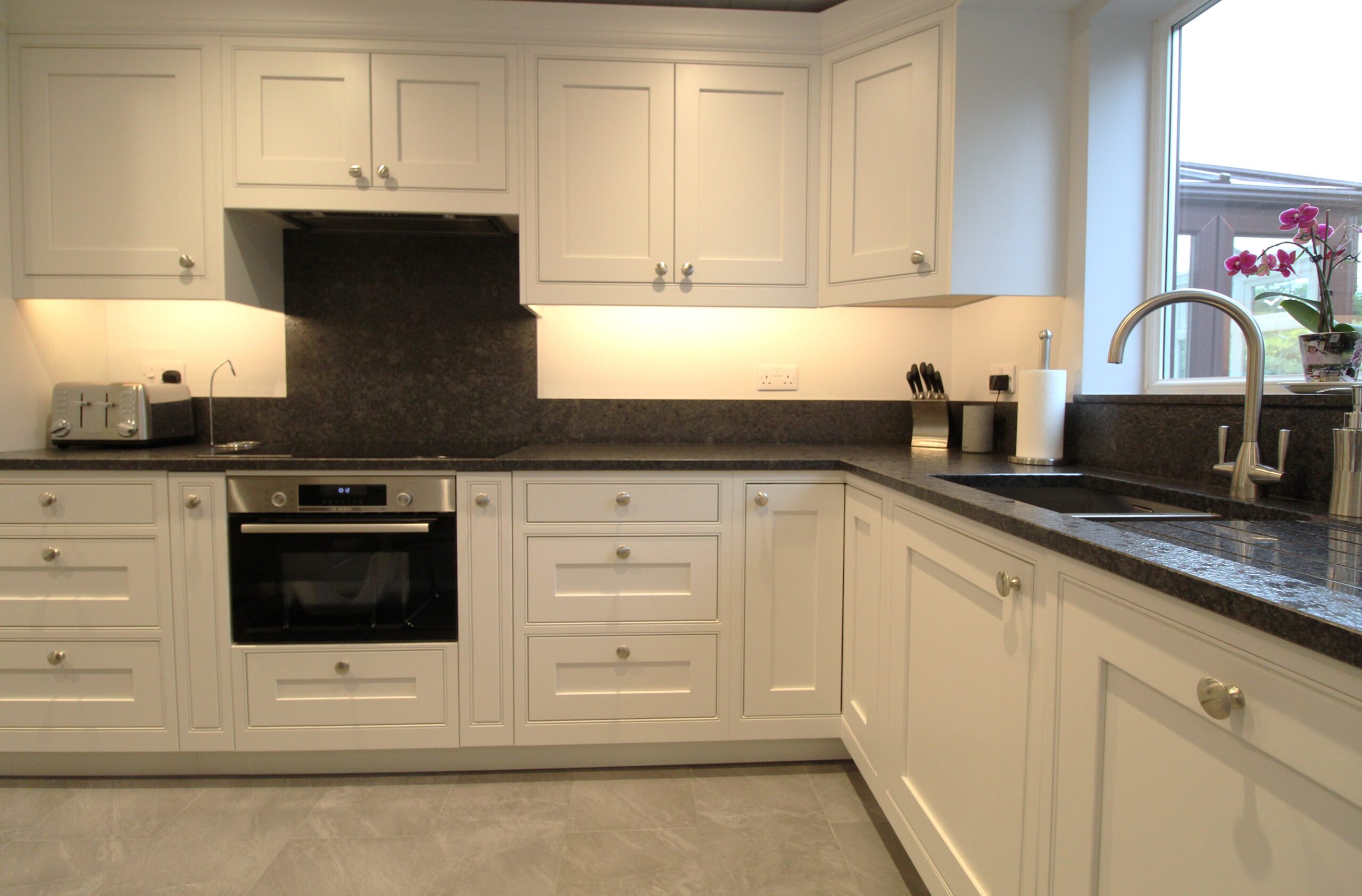 White painted inframe kitchen with black granite worktop, Bosch oven, induction hob and canopy extractor