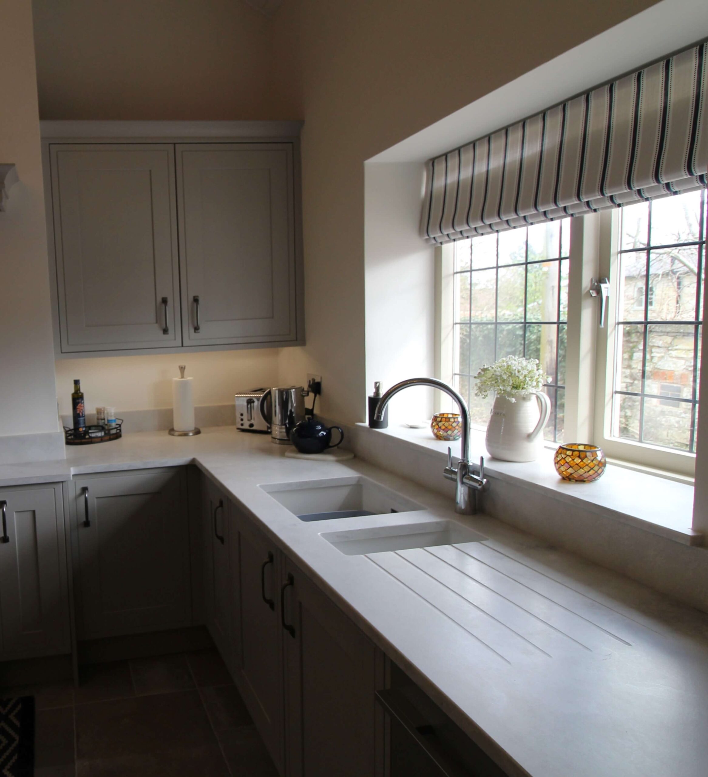 Soft grey painted kitchen with quartz worktop, white ceramic sink and chrome grohe tap