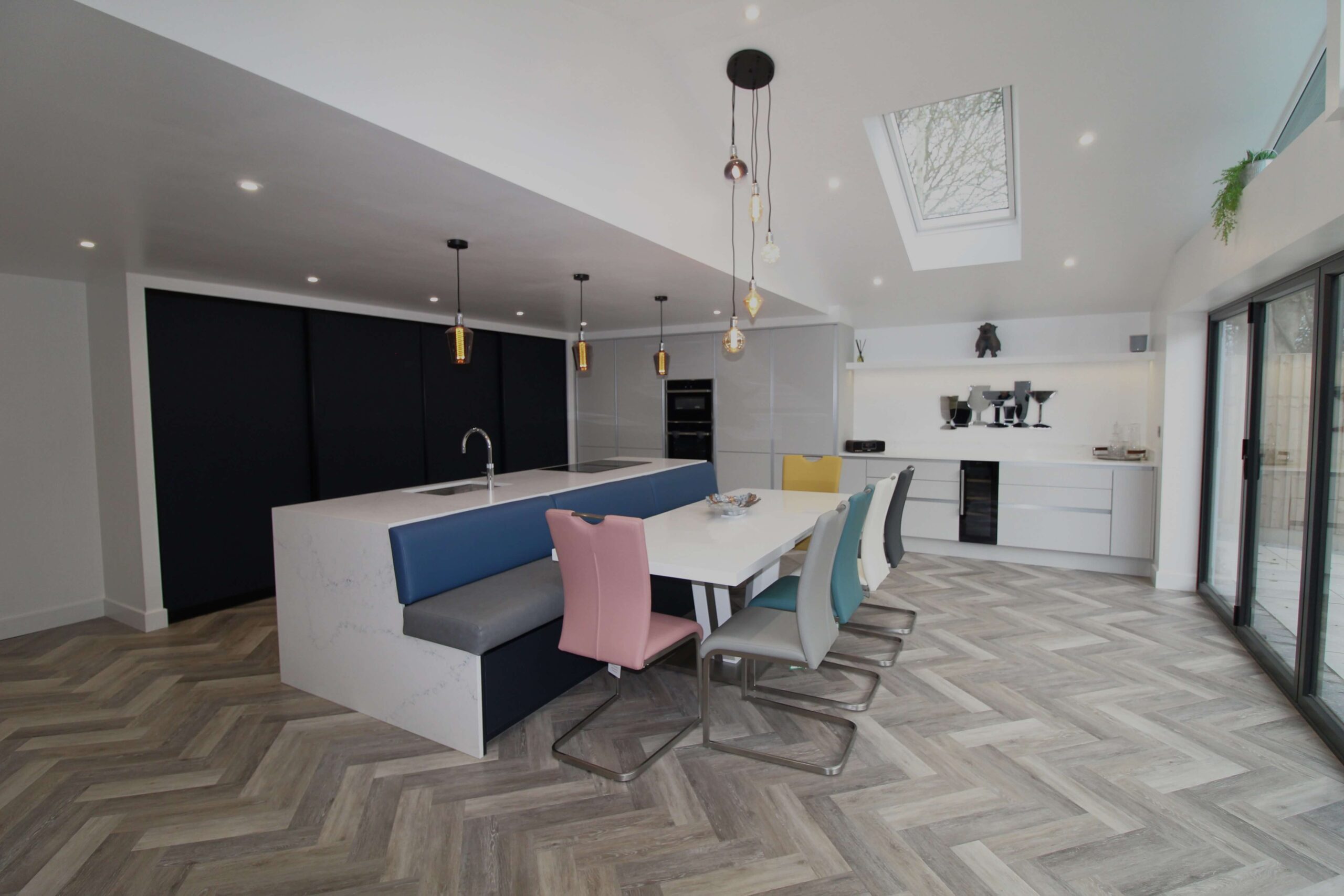 blue slab door with quartz kitchen island and pastel coloured seating around dining table